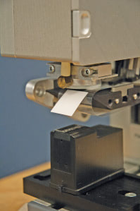 Die Cut Adhesive dispensed from Release Liner with Automatic Placement Strouse die cuts this adhesive for Lexmark to for their Inkjet cartridges.