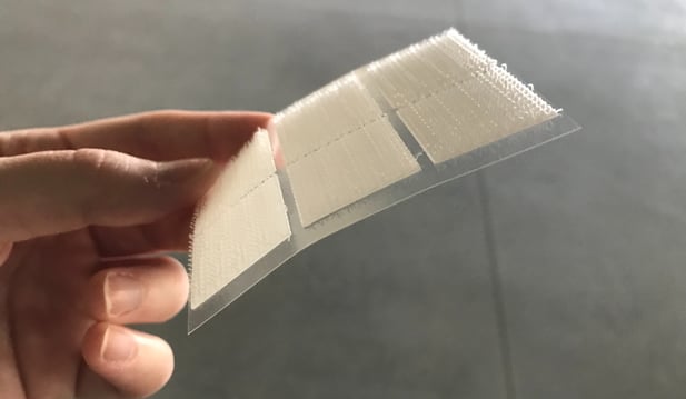A hand holding a kiss cut velcro adhesive