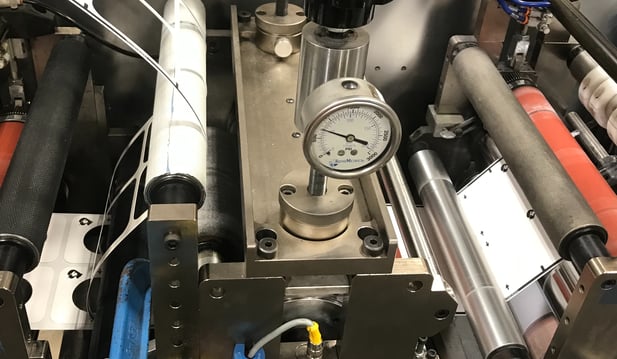 An adhesive enters a die and comes out kiss cut