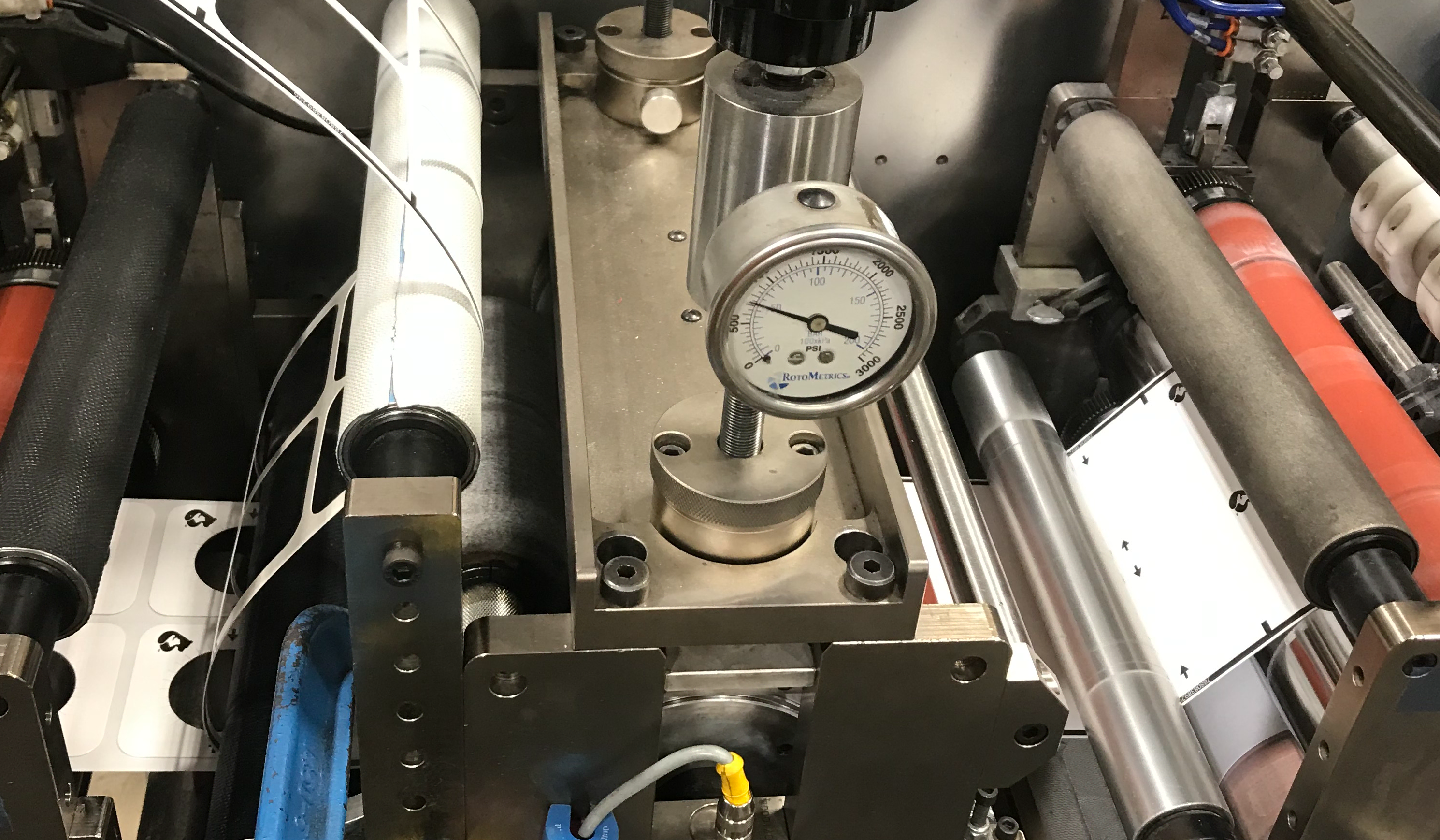 An adhesive enters a die and comes out kiss cut